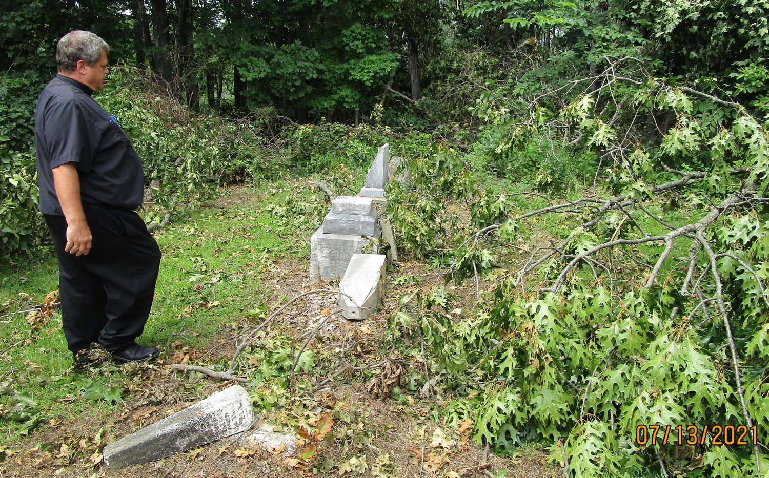 Father Gregory Oligschlaeger VF, pastor of Holy Rosary Parish in Monroe City and St. Stephen Parish in Indian Creek, surveys tree and headstone damage in the St. Peter Cemetery in Brush Creek following a July 9 thunderstorm.